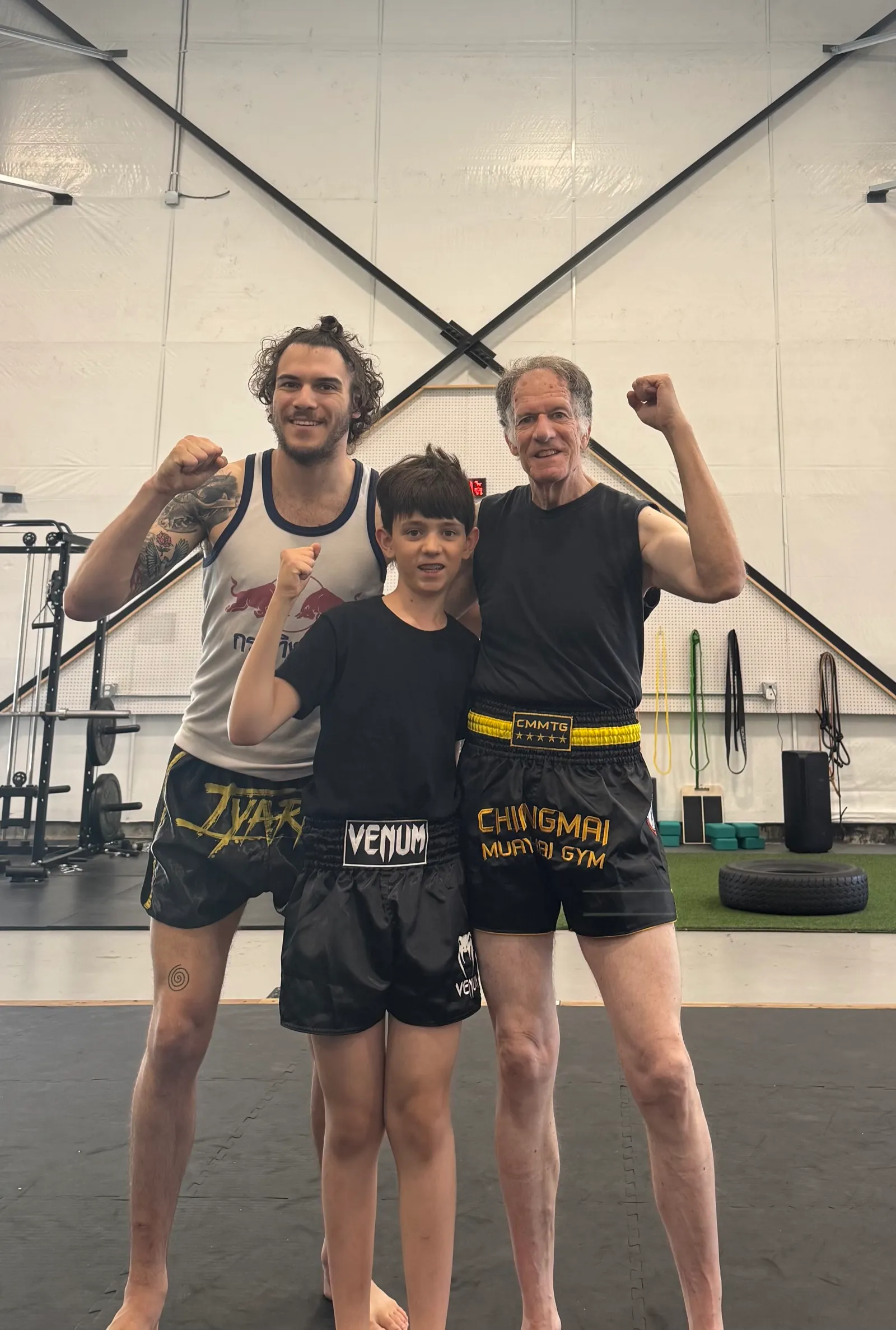Coach Nico Aliaga celebrating with two students of different generations after a class