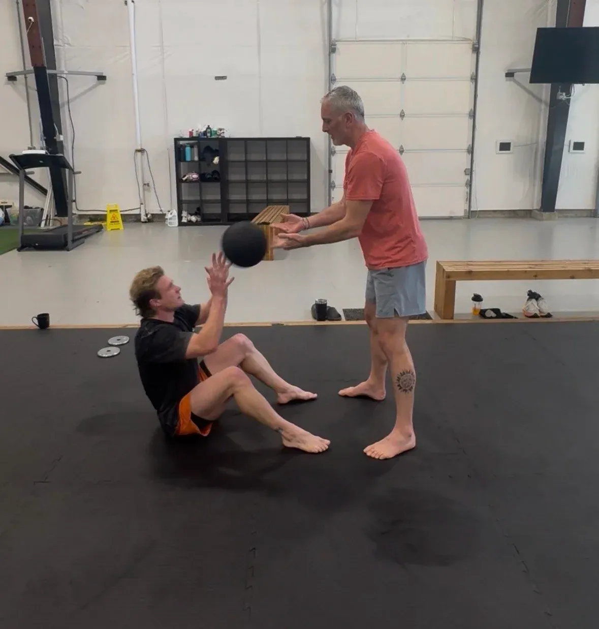 Coach guiding a student through a medicine ball exercise in a private lesson